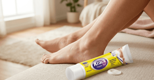 Krack Happy Feet specialist heel repair cream tube next to smooth bare feet on a couch